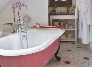 Une salle de bains ouverte sur la chambre avec une baignoire en fonte rose