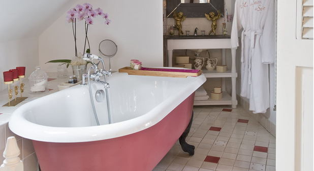 Une salle de bains avec une baignoire rétro rose et noire