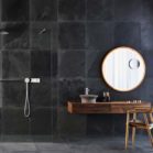 salle de bains aux murs carrelés de dalles noires avec un meuble en bois