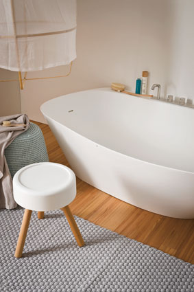 Une salle de bains style scandinave : plancher bois, baignoire en îlot blanche