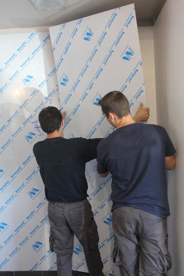 Deux personnes en train de poser des plaques murales en acrylique pour habiller la douche