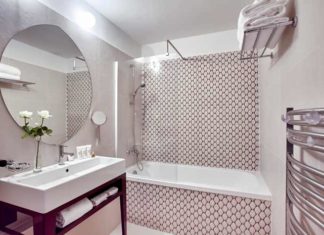 Salle de bain avec baignoire encastrée dans un décor carrelée aux motifs bicolores