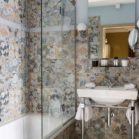 baignoire encastrée dans une salle de bains avec un patchwork de carreaux aux motifs de fleurs