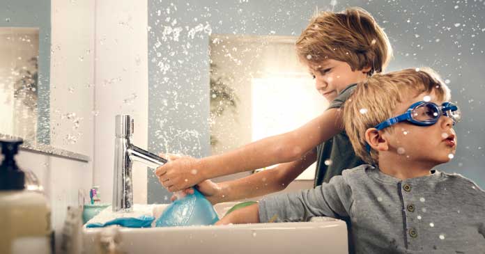 Jeunes enfants jouant avec l'eau devant un lavabo