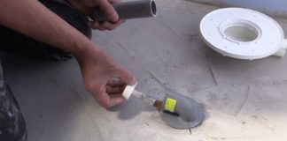 Main encollant un tube PVC à coller