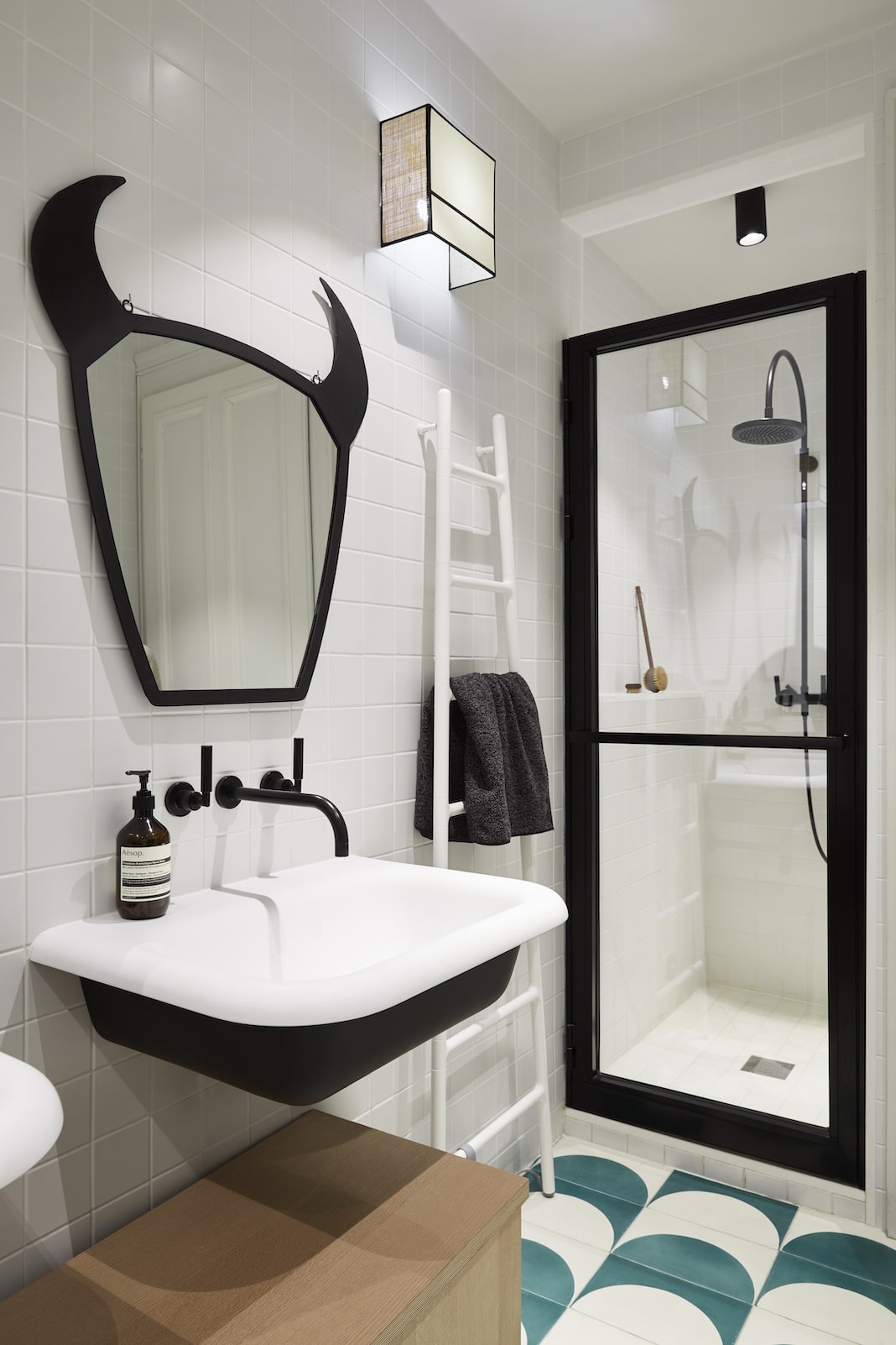 salle de bains design aux murs blancs avec un lavabo et une douche ceinturés de noir