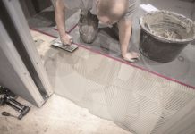 personne collant un panneau Qbaord sur le sol d'une salle de bain